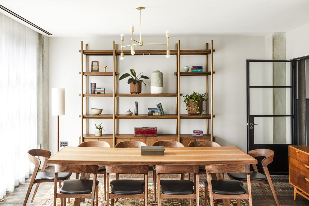 Decorative shelving sits on the far side of the meeting room, with a long table and 10 chairs around it in the middle. There is a full length window with lots of natural light.