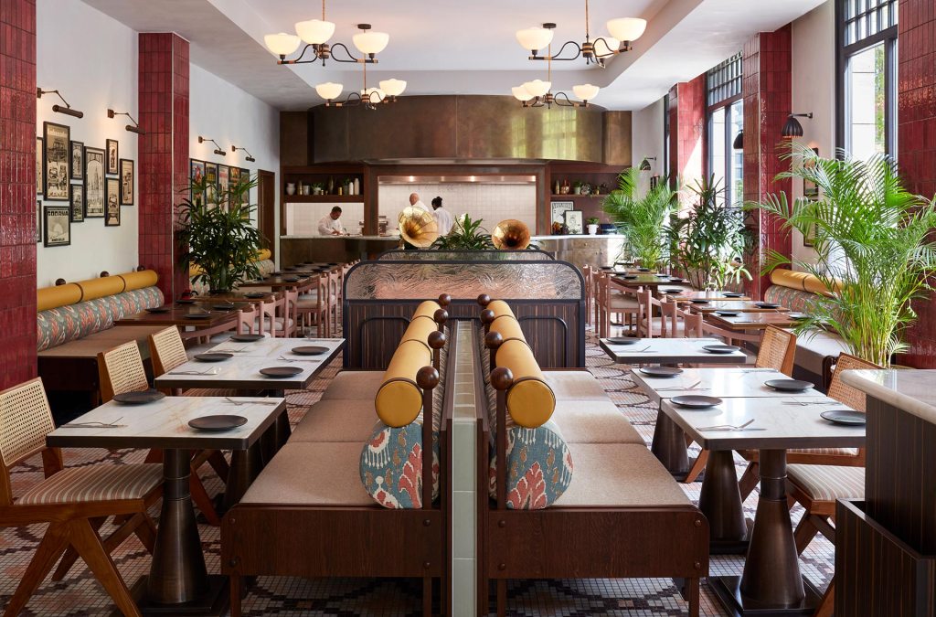 Wide view of the interior of House of Tandoor with tables, chairs, chandeliers and lots of natural light.